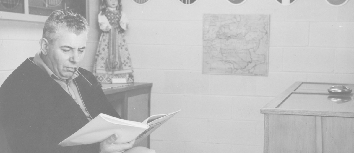 Man sitting in small archive room with pictures behind him