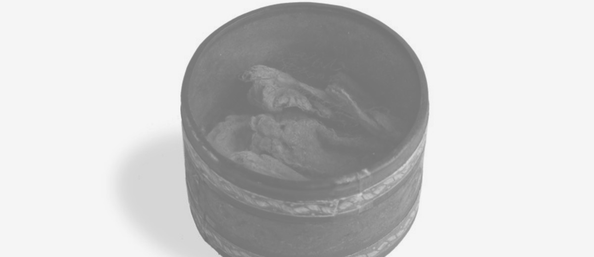 Image: round tin with clear lid and brown substance in bottom