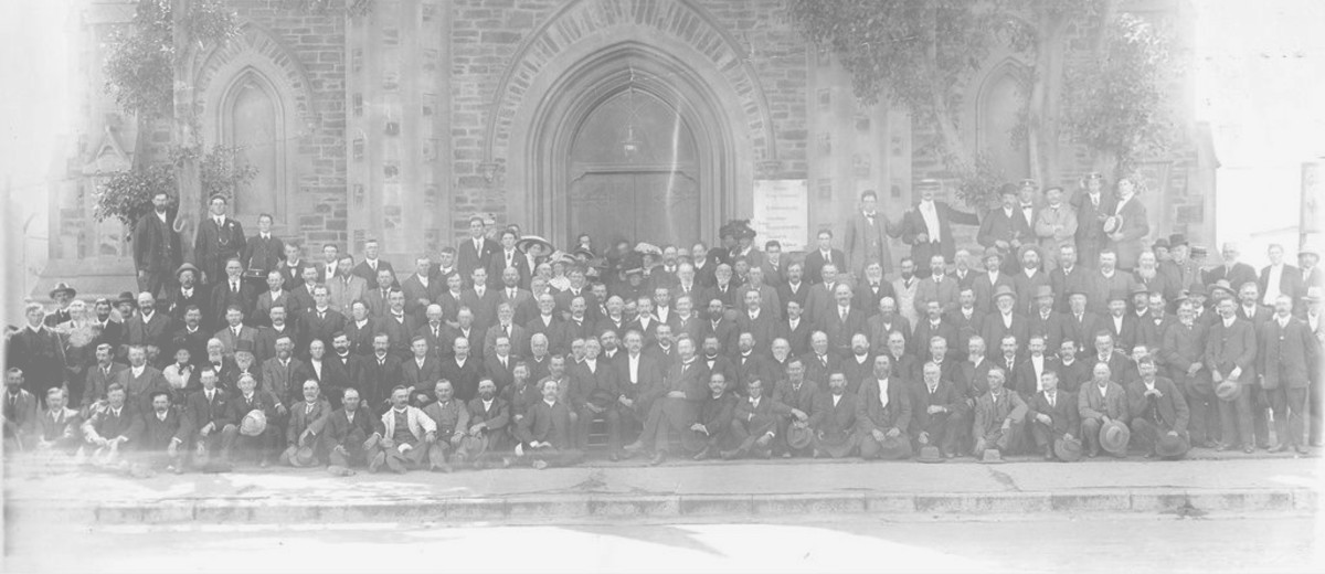 Image: crowd of congregation sitting in front of church facade and doorway