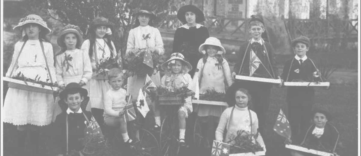 Image: A group of children stand near a house holding trays of flowers, two are on bicycles, and some are holding Australian flags