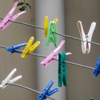 Image: Several colourful plastic clothing pegs are attached to a metal frame containing a number of separate clotheslines