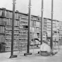 Image: shelves full of documents with person sitting on floor